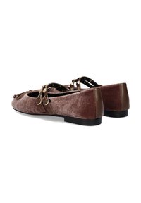 Bailarinas marrones de terciopelo con detalles de cuero marrón a juego y dos correas decorativas. Presentan un tacón bajo y una punta redonda. Superficie texturizada.
