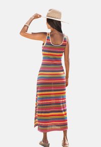 Maxi dress with a colorful striped pattern in red, blue, green, and yellow, made of lightweight fabric. Features a scoop neckline and side slit.