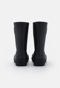 Une paire de bottes de pluie en caoutchouc noires vue de dos sur un fond blanc uni, avec une semelle texturée et une hauteur mi-mollet.