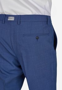 Blaue strukturierte Hose mit flachem Vorderteil, einer knöpfbaren Gesäßtasche und einem dezenten Karomuster. Verfügt über einen normalen Taillenbund und Gürtelschlaufen.