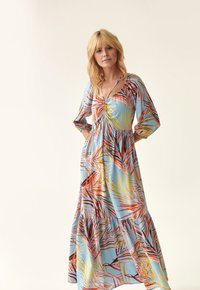 Maxikleid aus hellblauem Stoff mit elastischem Bund. Es hat einen lebhaften Druck von Palmblättern in Orange und Gelb und Dreiviertelärmel.