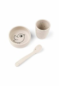 Juego de comedor de silicona en beige claro. Incluye un tazón con un gráfico de un pájaro, una taza con motas y una cuchara a juego con puntos.