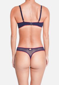 Ensemble de lingerie marine en matériau en maille transparente. Le soutien-gorge dispose de bretelles réglables et d'une bordure rouge en forme de vagues. Le slip possède un accent circulaire à l'arrière.