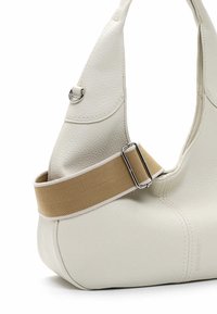 Borsa a tracolla in pelle bianca con una texture morbida, forma unica e una tracolla in tela beige. Presenta minuteria in argento e dettagli di cucitura.