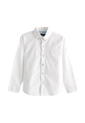 Valkoinen pitkähihainen nappikauluksinen paita, jossa vasemmassa rinnassa pieni kohokuvioitu pyöreä logo.