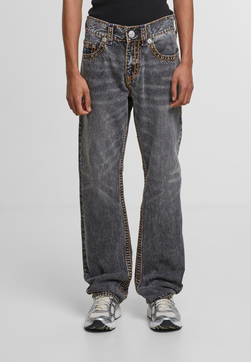 Baggy gray denim jeans with contrasting orange stitching, five pockets, and button closure. Features a straight leg and faded texture.