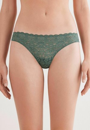 Groene kanten string met golvende randen, versierd met ingewikkelde patronen en een zachte textuur, ontworpen voor een comfortabele pasvorm.