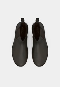 Pantofi slip-on din piele netedă, de culoare maro închis, cu vârfuri rotunde și panouri laterale elastice pentru o îmbrăcare ușoară. Prezintă o căptușeală interioară maro.