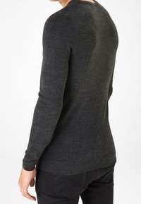 Ciemnoszary sweter wykonany z miękkiego materiału, z okrągłym dekoltem i ściągaczami przy mankietach. Prosty fason bez wyróżniających się wzorów czy akcentów.