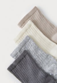 Fyra par ribbade strumpor i beige, krämfärgad, ljusgrå och mörkgrå, som visar en mjuk textur och kontrasterande färger på muddy.