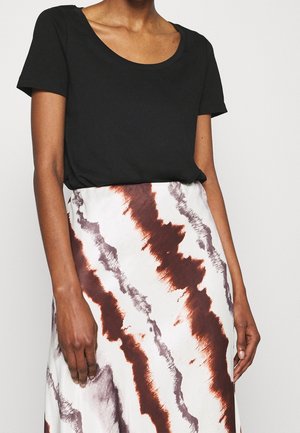 Czarny top z krótkim rękawem zestawiony z białą spódnicą ozdobioną falistym brązowo-szarym wzorem. Tkanina wydaje się gładka i lekka.