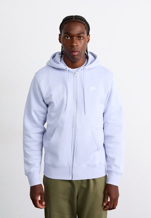Sweatshirt azul claro com fecho éclair, feito de um tecido macio, com um bolso frontal e cordões. Apresenta um pequeno logotipo da Nike em branco no peito.