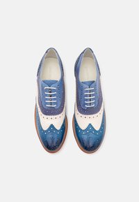 Scarpe in pelle con un design a gradiente blu, dettagli brogue, accenti beige chiaro e suole marroni. Chiusura con lacci e perforazioni circolari.