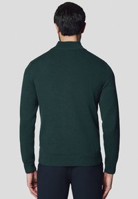 Ciemnozielony sweter z dzianiny z wysokim kołnierzem, prążkowanymi mankietami i dołem, charakteryzujący się teksturowanym materiałem i dopasowanym krojem.
