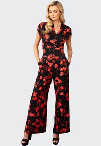 Tuta nera con motivo floreale rosso, maniche corte, top avvolgente, gambe ampie e tasche laterali; tessuto liscio, finitura lucida.