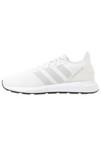 Witte sportieve schoen met een bovenwerk van mesh, drie grijze strepen, ronde neus en een gestructureerde hak. Beschikt over een zwarte rubberen loopzool.