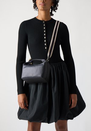 Black ribbed knit dress with a buttoned neckline, paired with a small black leather handbag with a structured shape and striped shoulder strap.