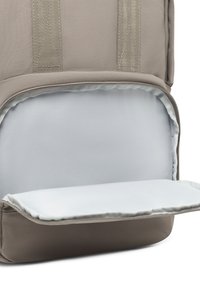 Interno di uno zaino in tessuto grigio con un compartimento imbottito di colore grigio chiaro per dispositivi elettronici. Presenta una cerniera liscia e cuciture rinforzate.