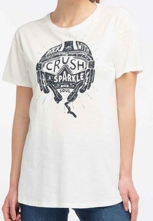 Persona con camiseta blanca con gráfico negro de gafas de esquí y texto "Rock with crush a sparkle and soul" en el frente.