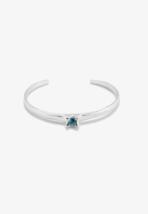 Bracelet manchette en argent présentant une pierre précieuse bleue centrale, une texture lisse, un design minimaliste et des extrémités légèrement arrondies.