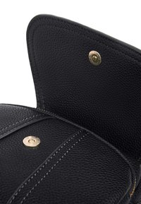 Borsa a mano in pelle nera con superficie texturizzata, accessori in oro e cuciture a contrasto. Chiusura magnetica e interno liscio visibile.