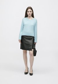 Svetlo modri, pleteni pulover z V-izrezom, črna usnjena svinčnik krilo s stranskim razporkom, črne visoke pete in majhna črna torbica.