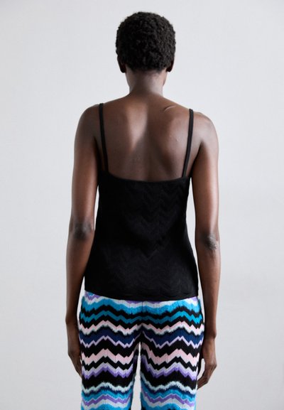 Black spaghetti strap tank top with a textured zigzag pattern, paired with multicolored zigzag patterned pants in blue, pink, and black.