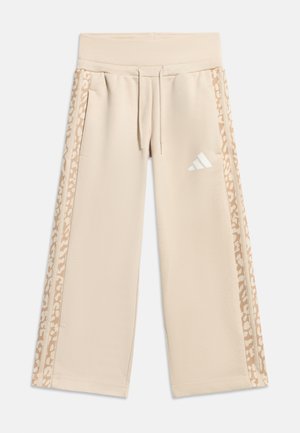 Beige vidbukse joggebukse med snøring i midjen, leopardmønstrede striper på sidene og hvit Adidas-logo på høyre lår.