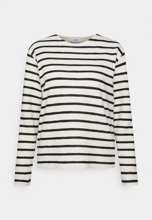 Chemise blanche à manches longues avec des rayures horizontales noires et un col rond, présentée sur un fond gris clair uni.