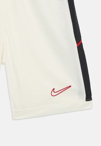Shorts Nike blancs avec des panneaux latéraux noirs. Présente des accents rouges et un logo. Fabriqué en tissu respirant avec une texture lisse.