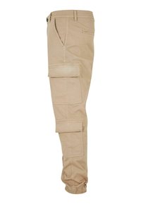Beige Cargo-Hosen mit Seitentaschen, elastischen Bündchen und einer glatten Baumwollstruktur. Entworfen für Funktionalität und Komfort.