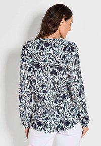 Blusa a maniche lunghe con un motivo floreale astratto nei toni blu navy, bianco e azzurro; tessuto leggero con una vestibilità morbida e orlo arrotondato.