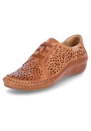 Zapato de cuero marrón con diseños florales recortados, detalles de cordones y un tacón cuña. Presenta un borde cosido para mayor textura y durabilidad.