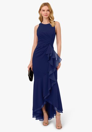 Abito da sera blu navy con balze stratificate, corpetto aderente e orlo asimmetrico. Realizzato in tessuto leggero, presenta un collo rotondo e un design senza maniche.