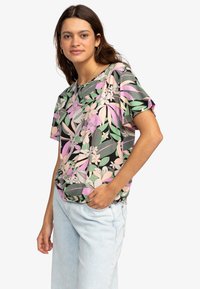 Korte mouwen t-shirt met een zwarte basis en een kleurrijk bloemenpatroon in roze, groen en crèmekleurig. Relaxte pasvorm met ronde halslijn.