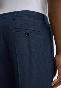 Marineblaue Hose aus strukturiertem Stoff. Verfügt über eine Gesäßtasche mit Knopf, Slim-Fit und ein maßgeschneidertes Design.