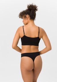 Black cotton bralette with adjustable straps and matching thong, featuring a seamless design and smooth texture, viewed from the back.