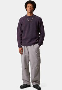 Maglione a maglia viola macchiato con collo a girocollo a coste, abbinato a pantaloni cargo grigi chiari con tasche laterali e una vestibilità comoda. Scarpe nere.