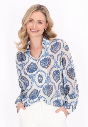 Lettet, gennemsigtig blouse med blå blomster mønstre på en hvid baggrund. Med krave, knaplukning og lange ærmer.