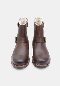 Stivaletti in pelle marrone con fodera in shearling, caratterizzati da due cinturini decorativi in ottone sul lato e una suola in gomma robusta.