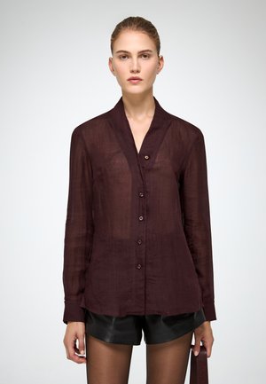 Camicia button-up trasparente bordeaux con colletto e maniche lunghe, dotata di bottoni frontali e orlo dritto, abbinata a pantaloni shorts neri.
