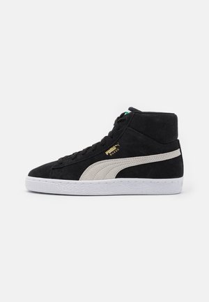 Baskets montantes en suède noir avec une bande blanche Puma, semelle blanche, lacets noirs et logo doré Puma Suede sur le côté.