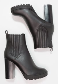 Czarne botki za kostkę z teksturowanej skóry, pionowymi szwami, masywnymi wysokimi obcasami i wytrzymałą podeszwą.