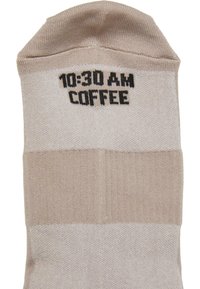 Calzini beige e crema con testo nero che legge "10:30 AM COFFEE" vicino al bordo.