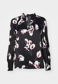 Svart blomstermønstrete bluse med hvite og røde blomster, lange ermer med rynkede mansjetter, og en nøkkelhullsdetalj i halsen.