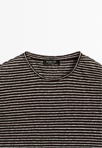 Donkerbruine en witte horizontale gestreepte shirt met ronde hals en Massimo Dutti-label aan de binnenkant van de kraag, plat gelegd op een witte achtergrond.
