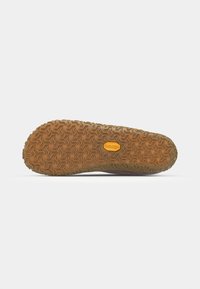 Semelle de chaussure en caoutchouc avec une surface marron texturée, présentant des motifs en zigzag et un logo jaune au centre ; conçue pour l'adhérence.