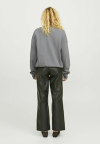 Oversized šedá mikina s spadlými rameny, spárovaná s vysokým pasem a širokými černými koženými kalhotami. Texturovaný design a přiléhavý pas.
