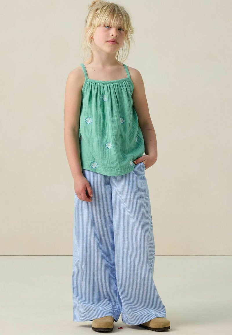 Débardeur en tissu vert avec broderie de coquillage, associé à un pantalon large à rayures bleues et blanches. L'ensemble présente des bretelles fines et une coupe décontractée.