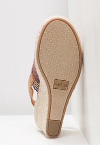 Sandale espadrille à talon compensé, dotée d'une semelle beige texturée avec une adhérence en caoutchouc, tige en cuir brun et détails latéraux tissés colorés.